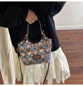 Detailed view of the geometric rhombus pattern fabric and leather handle of this bucket bag