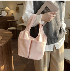 Dettaglio della borsa tote in nylon rosa chiaro con due tasche frontali in un caffè accogliente