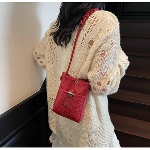 Red woven phone crossbody bag with metal buckle and drawstring on model at stairs