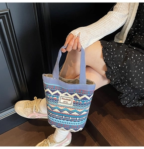 Detail of canvas bucket bag with ethnic geometric pattern and leather brand label
