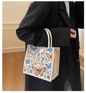 Detailed close-up of embroidered butterflies and floral patterns on an ivory linen tote bag