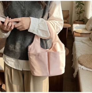 Dettaglio della borsa a secchiello in tela rosa chiaro con due tasche anteriori
