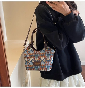 Close-up of geometric woven bucket bag featuring brown knotted handle and logo detail