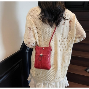 Detailed view of red textured crossbody phone bag with silver metallic buckle on model
