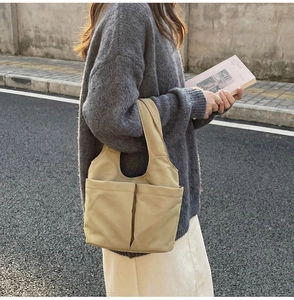Dettaglio della borsa tote in nylon kaki chiaro con ampie tasche frontali casual