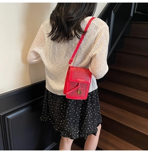 Detail of red crocodile texture crossbody phone bag with gold metal pendant on shoulder