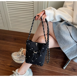 Detail of black floral canvas bag with woven strap and silver snap button closure