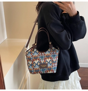 Detail of colorful geometric woven pattern and leather handle on a stylish bucket bag