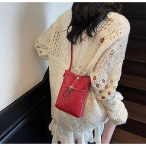 Detail of red woven mini crossbody bag with drawstring clasp and adjustable shoulder strap