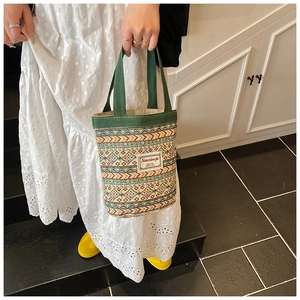 Détail d'un sac à main tissé coloré avec motifs ethniques et anses en toile verte