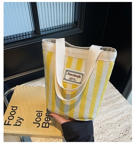 Close-up of yellow and white striped canvas tote bag featuring dual webbing handles
