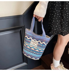 Detail of ethnic geometric canvas bucket bag with wide blue handles and logo patch