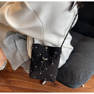 Detail of black floral crossbody bag with white flower hardware and woven strap