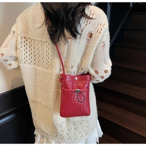 Close-up of red woven texture mini crossbody phone bag on model's back with metal clasp