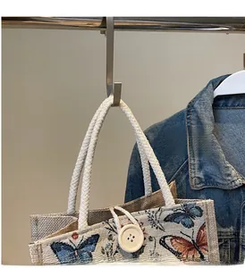 Detail of linen tote bag featuring butterfly print and rustic rope handle with button