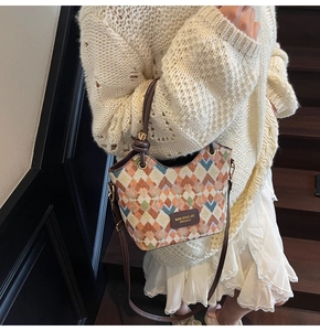 Close-up of quilted bucket bag in multi-color weave with brown leather strap