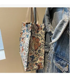 Detail of jacquard tote bag with butterfly patterns hanging next to a denim jacket