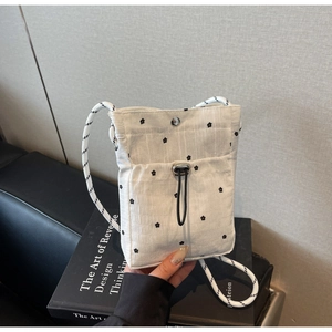 Close-up of white floral crossbody bag with woven rope strap and adjustable buckle detail