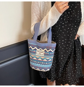 Close-up of ethnic knit bucket bag with blue geometric patterns and a woven label