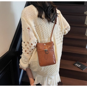 Detailed back view of a brown woven leather crossbody bag styled on a cream knit sweater