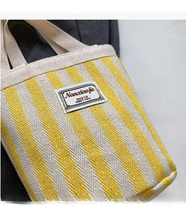 Detail of yellow and beige striped canvas tote bag featuring a stitched logo patch