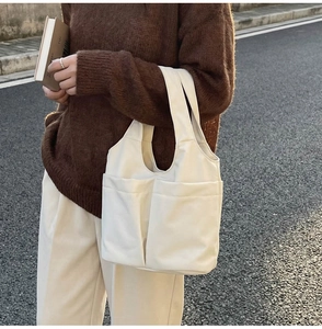 Dettaglio della borsa tote minimalista color crema con doppie tasche frontali