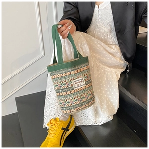 Détail d'un sac cabas tissé avec des motifs géométriques colorés porté par un mannequin