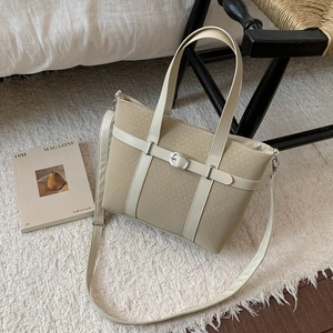Detail of beige woven tote bag with smooth leather trim and silver buckle accent