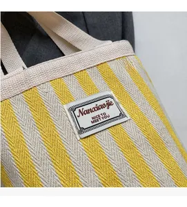 Detail of yellow and beige striped canvas tote bag with woven label and thick texture