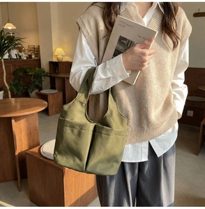 Dettaglio della borsa a secchiello in tela verde militare con tasche per l'uso quotidiano