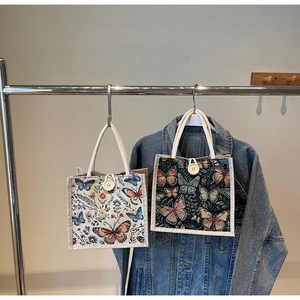 Close-up of linen tote bag featuring vintage butterfly embroidery and wooden button closure