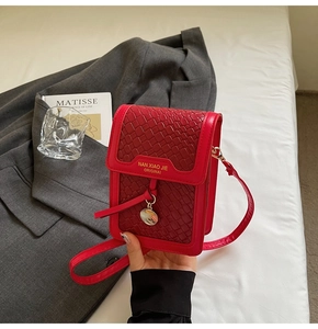 Close-up of red woven texture crossbody phone bag with gold hardware held by hand