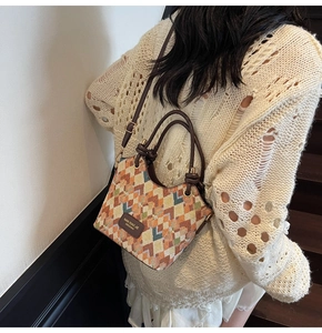 Detail view of multicolored geometric quilted bucket bag on model in a stylish indoor setting
