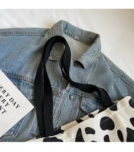 Detail of wide black fabric shoulder strap on a cow print tote bag for daily use