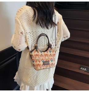 Detail showing vintage geometric pattern bucket bag with leather handles and brand tag