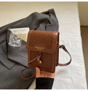 Detail of dark brown faux-crocodile texture crossbody bag with gold brand lettering