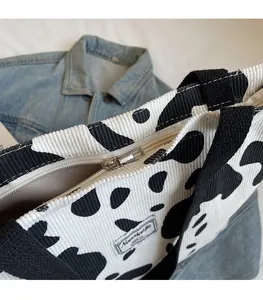 Close-up of smooth metal zipper and cow print texture on large tote shoulder bag