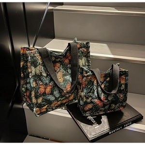 Detail of two-piece tote bag set featuring vibrant butterfly prints and black canvas handles