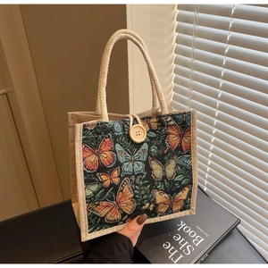 Detail of embroidered butterfly linen tote bag with woven rope handles and wood button