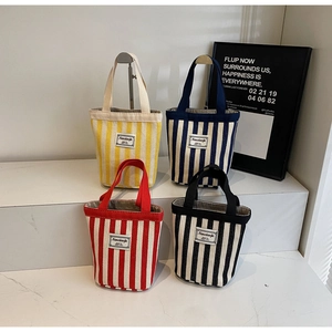 Detail of four striped canvas tote bags in yellow, blue, red and black with sturdy handles
