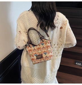 Detail of woven bucket bag featuring multicolor diamond patterns and leather logo tag