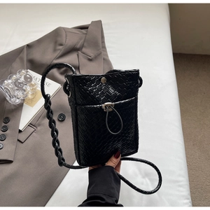 Detail of black woven leather texture and silver twist lock on mini crossbody bag