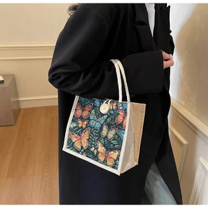 Linen handbag featuring vivid butterfly print and soft rope handles shown on shoulder