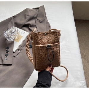 Close-up of brown woven leather texture and drawstring pocket on crossbody phone bag