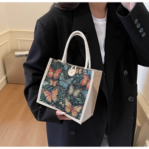 Close-up of vibrant butterfly embroidery on linen tote bag with wooden button and cotton rope