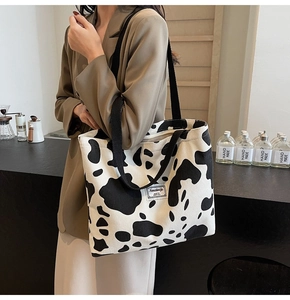 Detail of cow print tote bag with woven shoulder strap and logo patch decoration