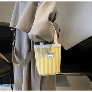 Detail showing yellow striped canvas tote bag with woven handles and brand label