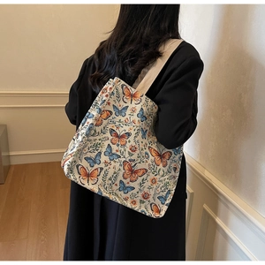 Rear view of model wearing a large tote bag with colorful butterfly and floral patterns