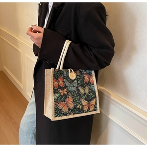 Close-up of a linen tote bag with colorful butterfly prints and woven rope handles