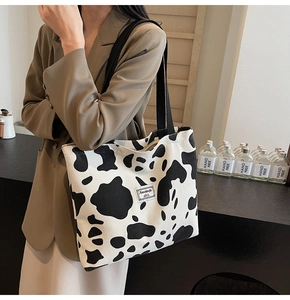 Close-up of black and white cow print tote bag with corduroy texture and brand label